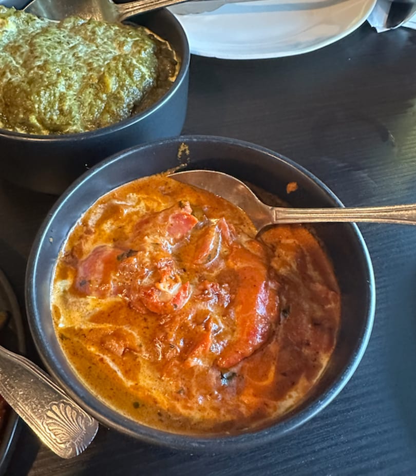 Two bowls of Indian food, one with orange curry and the other with green spinach dish.